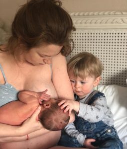 Jess sat with her toddler breastfeeding her newborn